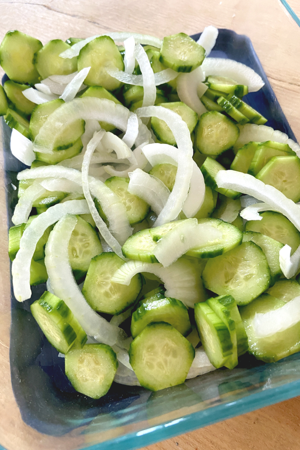 slices of cucumbers and onions in a dish 