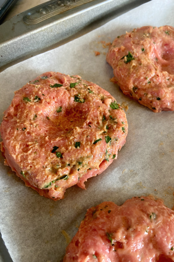 raw burgers with indention in center 
