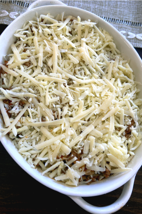 grated cheese on spaghetti in baking dish 
