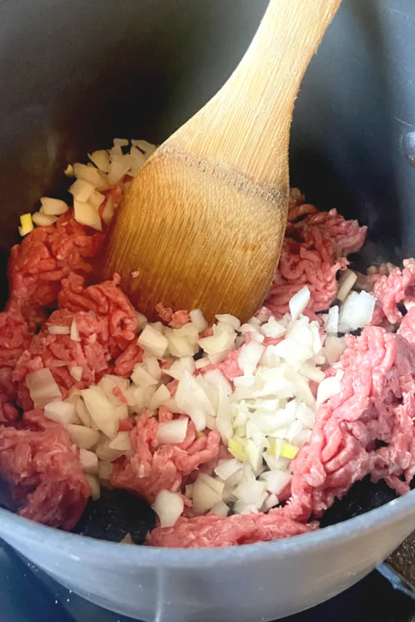 raw ground beef and diced onion in a pot