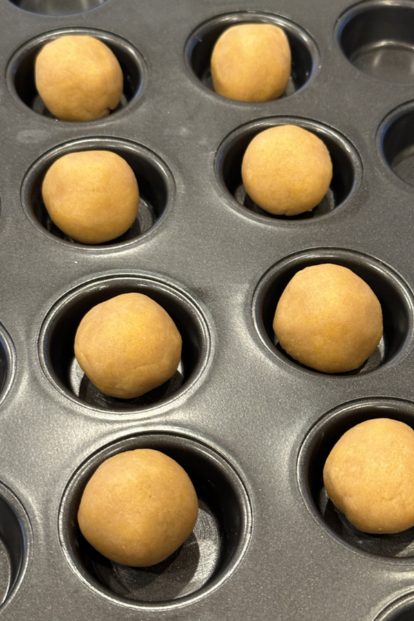 cookie dough balls in a mini muffin pan 