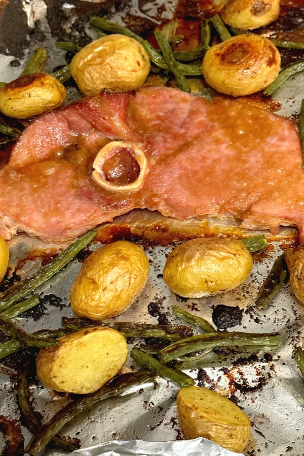 bone in ham steak and vegetables on a sheet pan