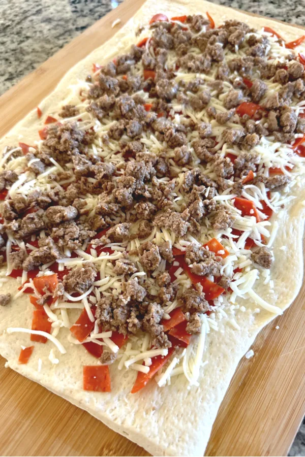 sausage pepperoni and cheese on pizza dough for an appetizer for two