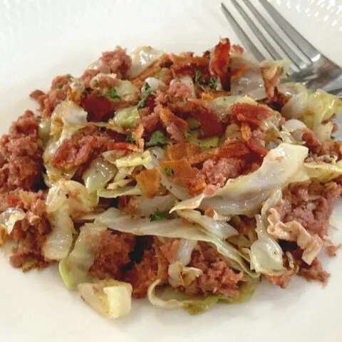 fried corned beef and cabbage on a white plate with a fork
