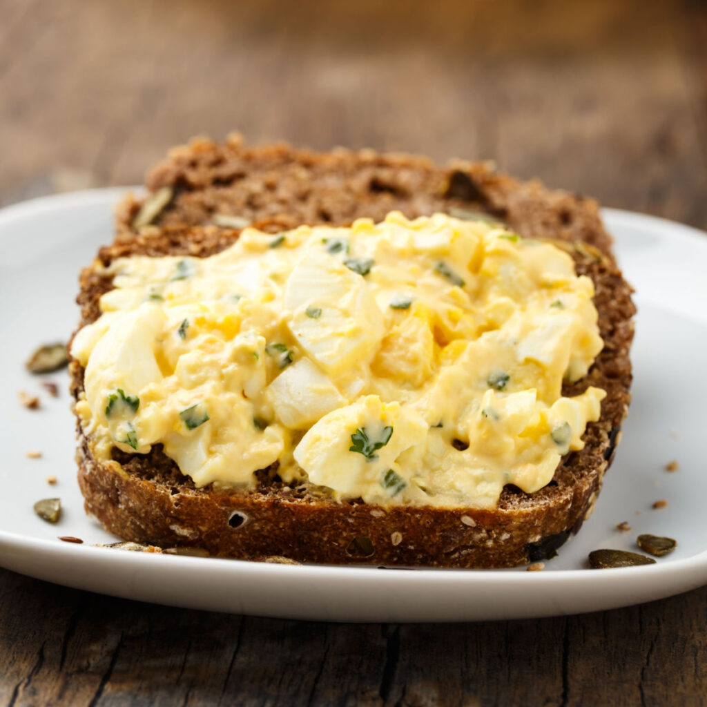 Deviled egg salad spread on a piece of wheat bread