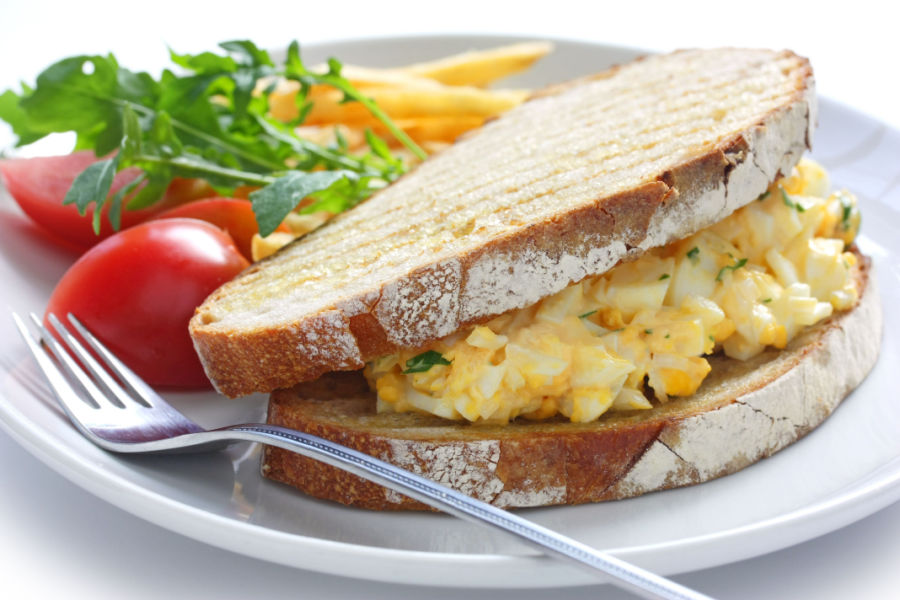 deviled egg salad sandwich, tomatoes and french fries on plate