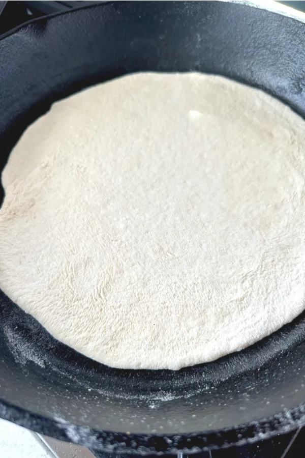 circle of flat dough in cast iron skillet