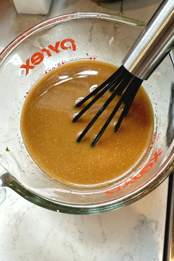 brown sauce in measuring cup with a whisk