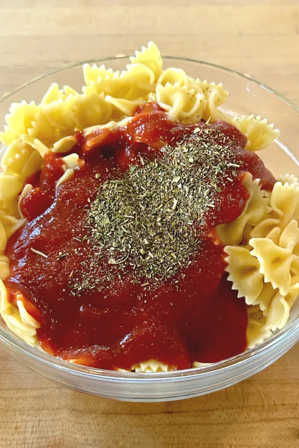 Italian seasoning on marinara sauce and bow tie pasta