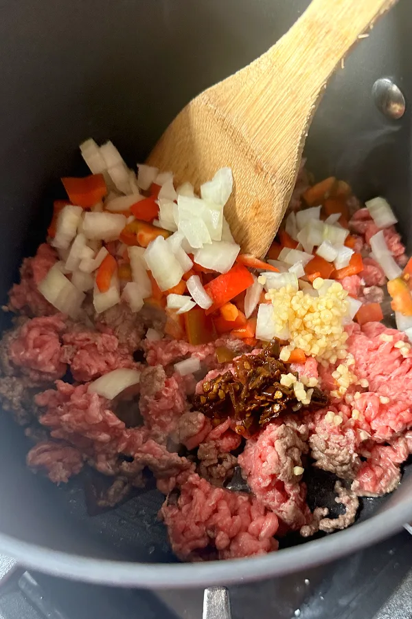 diced onions, peppers, ground beef in pot