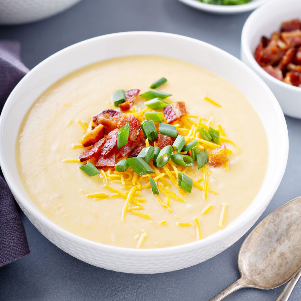 crock pot potato soup garnished with cheese, bacon and green onions