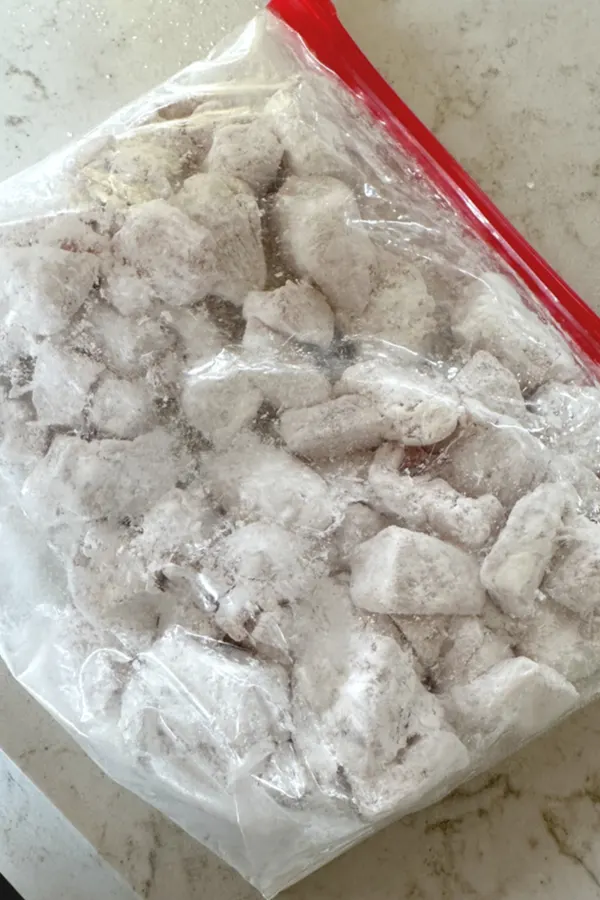 cornstarch covered pieces of chicken in plastic bag