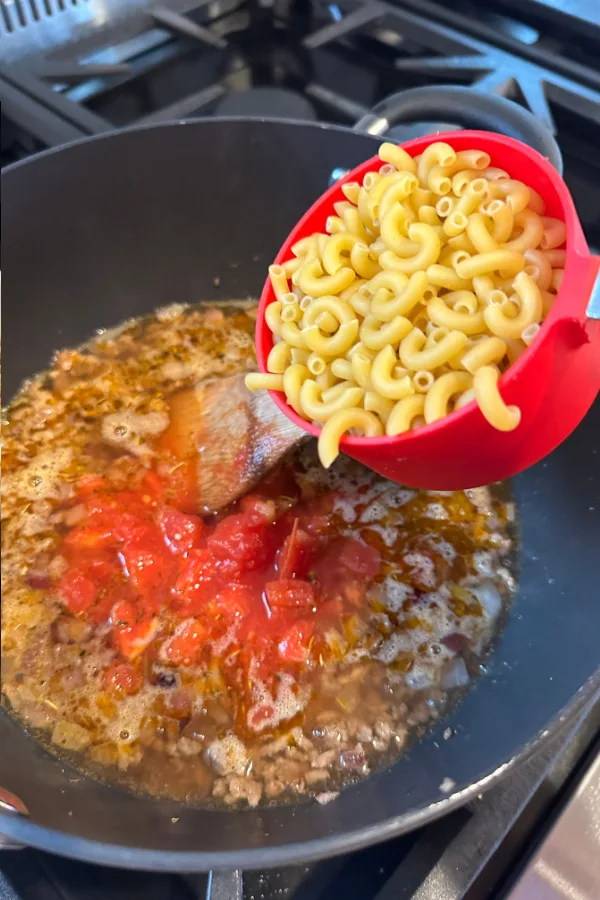 dry elbow macaroni pouring in skillet 