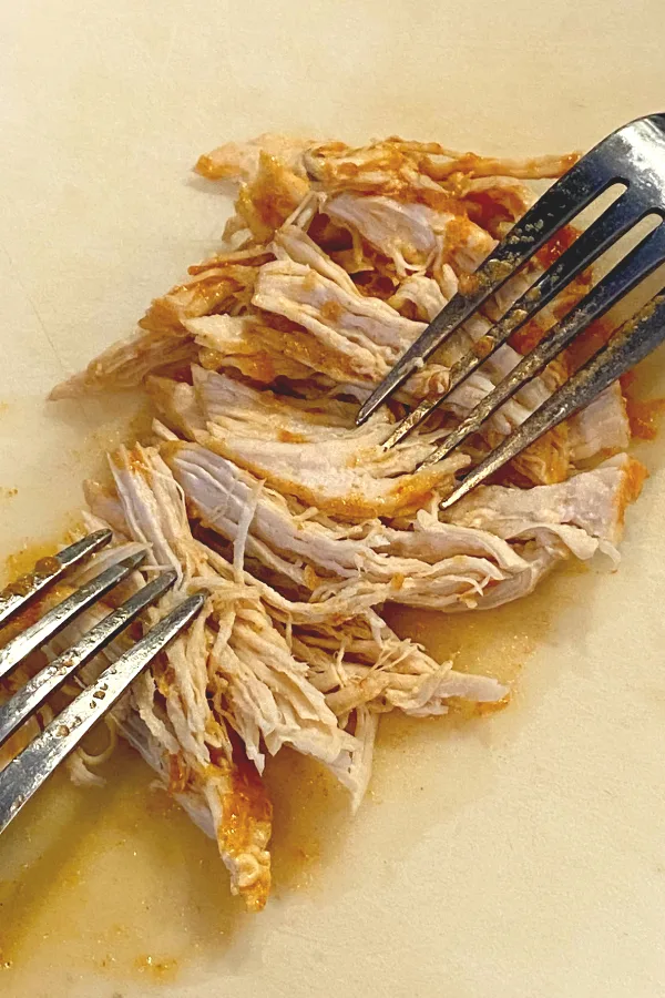 shredding cooked chicken with two forks